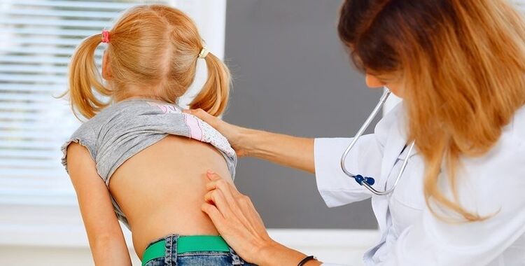 doctor examining the back of a boy with lower back pain